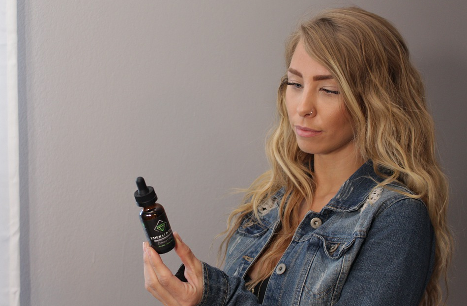 woman looking at CBD oil bottle